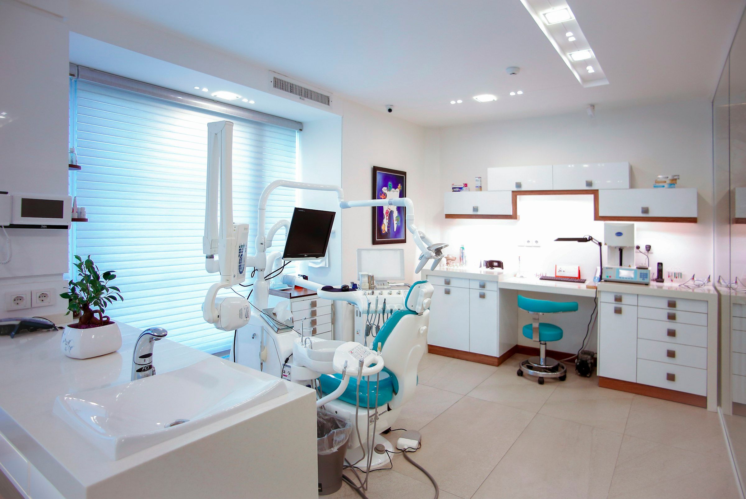 Consultorio dental con sillón dental, lavabo y muebles blancos